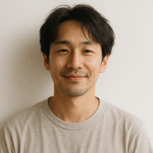 白い壁の前で柔らかい光に包まれながら、自然体の表情を見せる日本人男性の写真風イメージ